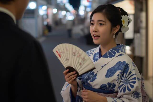 浴衣を着てスーツ姿の男性と話す女性