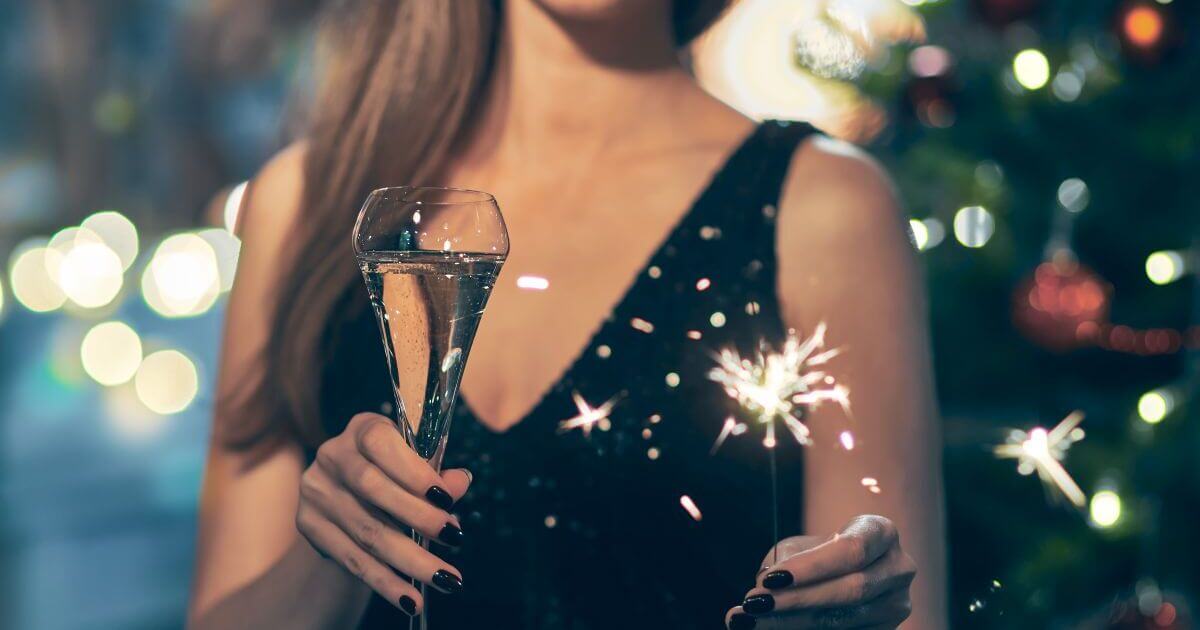 シャンパンと花火を持つドレスの女性