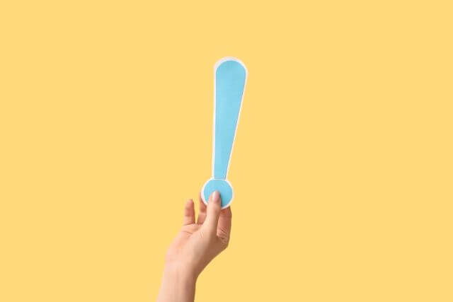 女性が持つ水色のビックリマーク