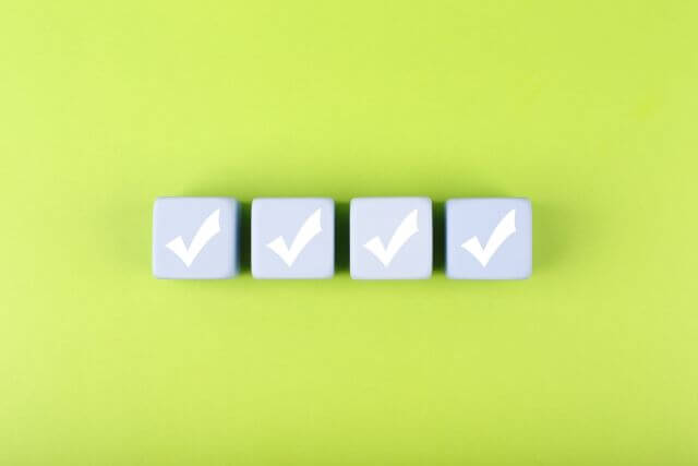 緑の背景の前にある4つの青いチェックマーク