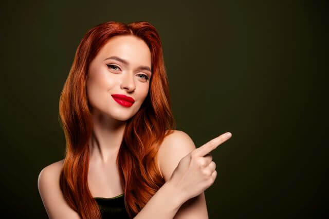 横を指さす女性