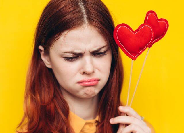 ハートのスティックを持ちながら落ち込む女性