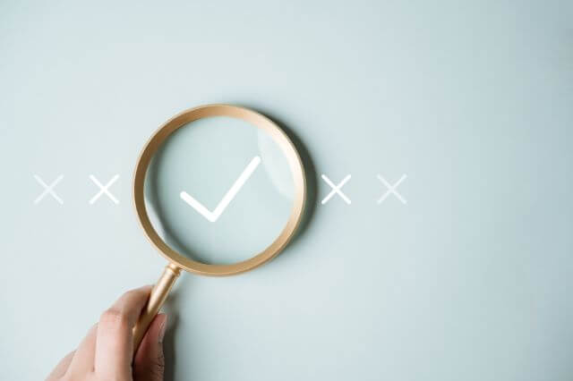 バツ印とチェックマークを見ている虫眼鏡